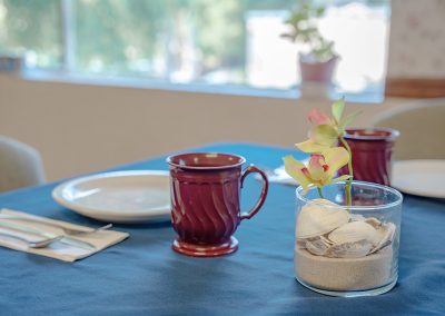 The dining room of the Woodland Nursing and Rehab facility showing linen table cloths and a set table